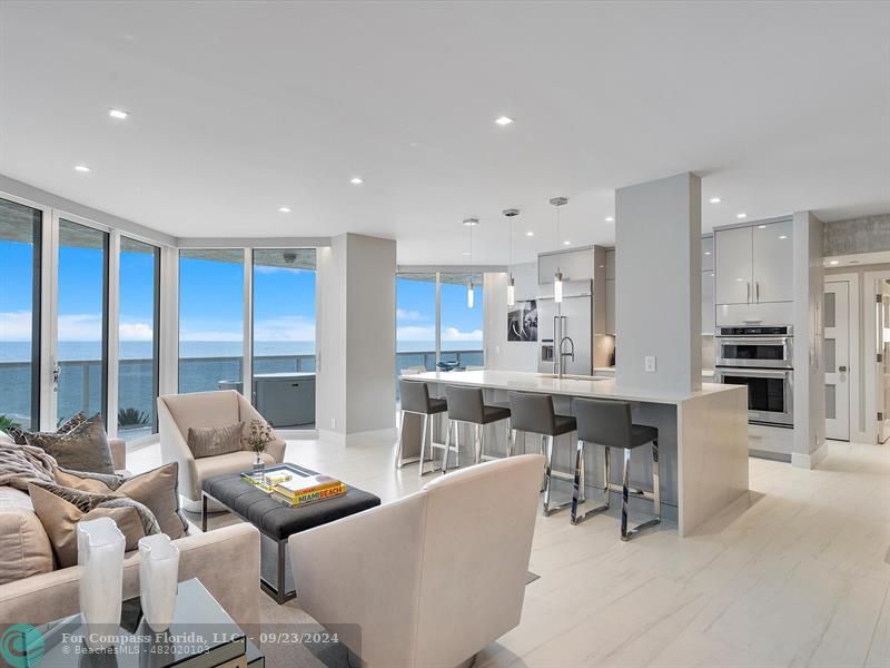 a living room with furniture kitchen view and large windows