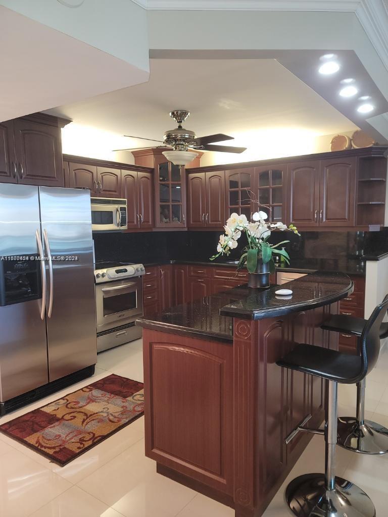 a kitchen with stainless steel appliances kitchen island granite countertop a stove refrigerator and cabinets