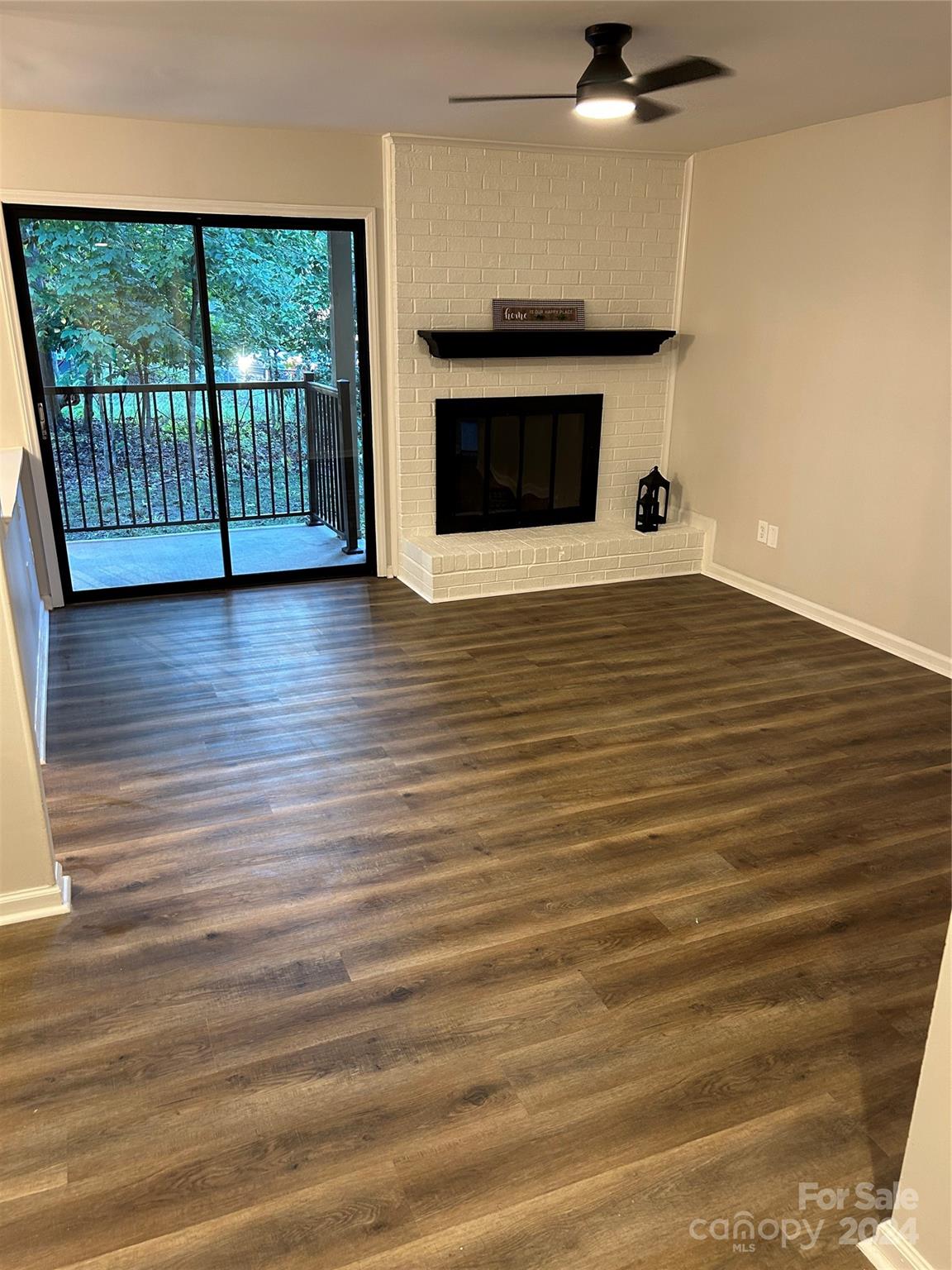 a view of empty room with wooden floor and fireplace