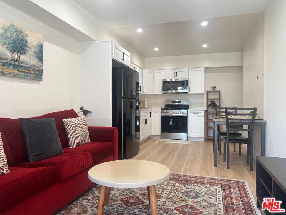 a living room with stainless steel appliances furniture a fireplace and a kitchen view