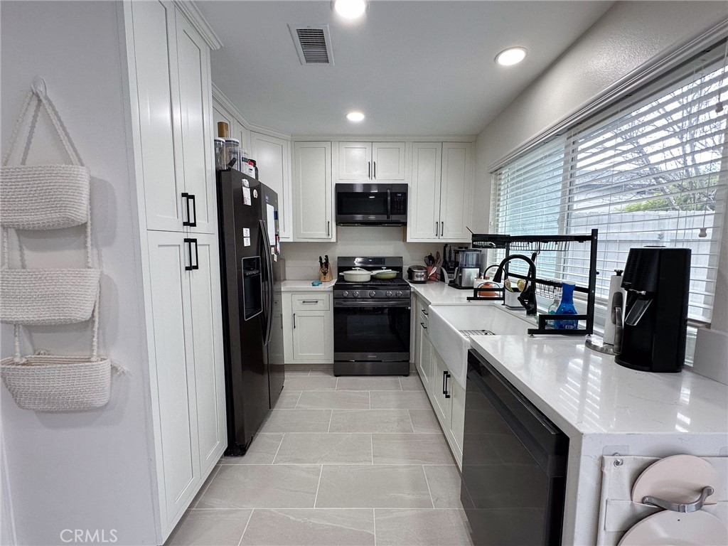 a kitchen with stainless steel appliances granite countertop a refrigerator a sink a stove and microwave