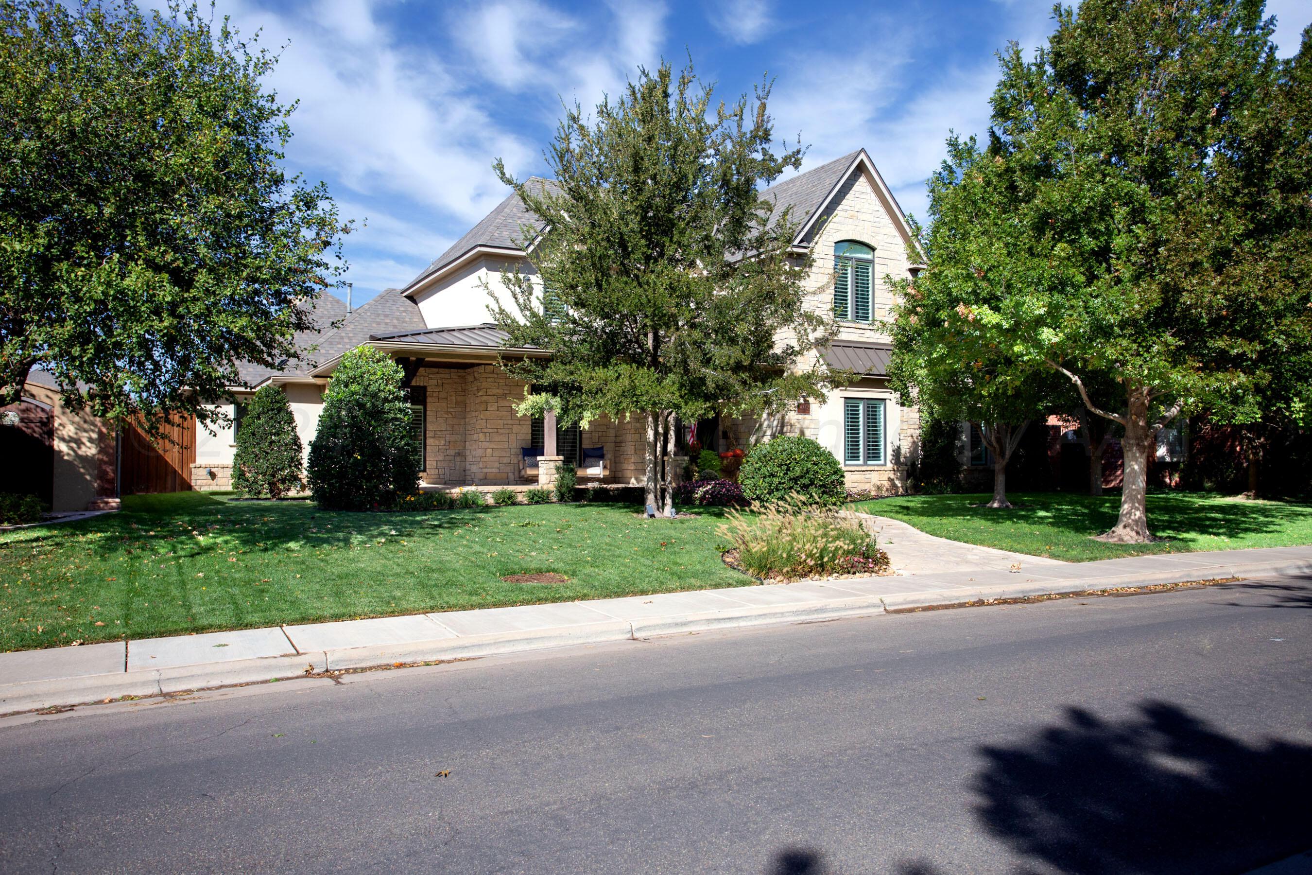 a view of a house with a yard and large trees