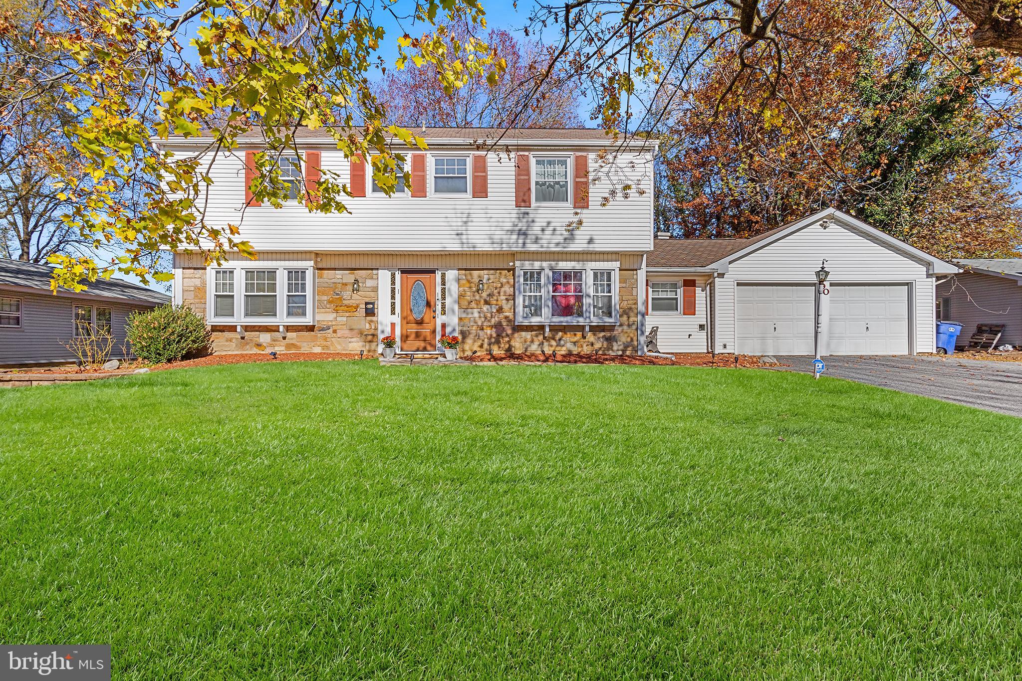 a front view of a house with a big yard and large trees