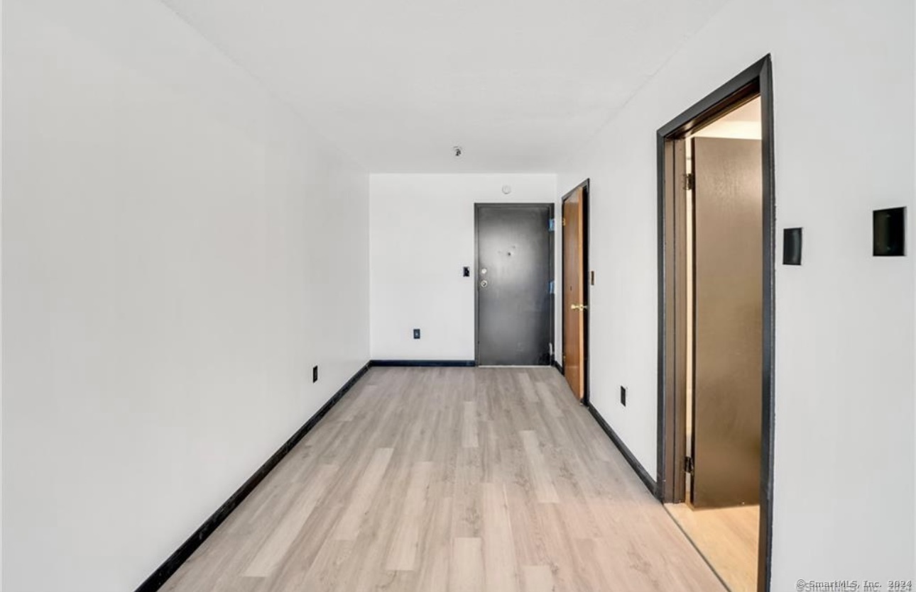 a view of a hallway with wooden floor and a bathroom