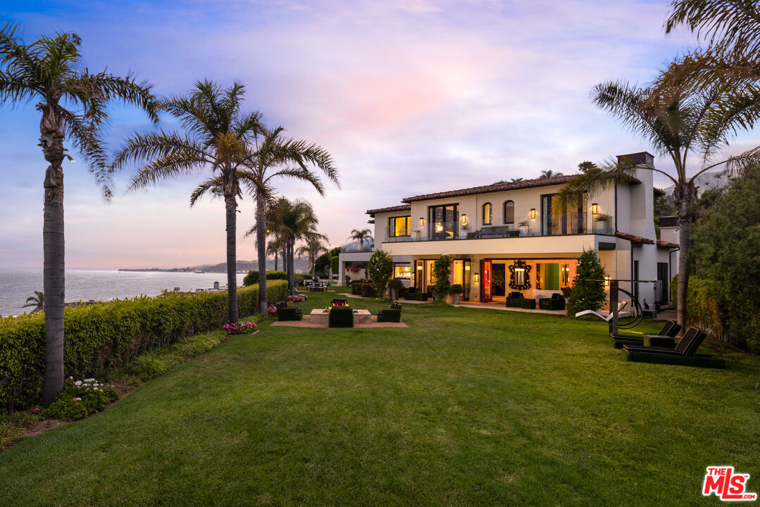 a view of a big house with a big yard and palm trees