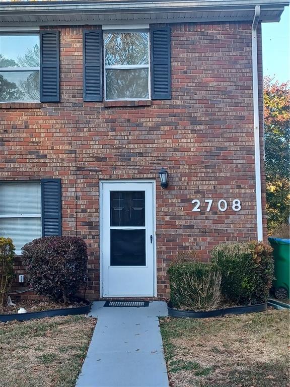 a view of a brick house with plants in front of it