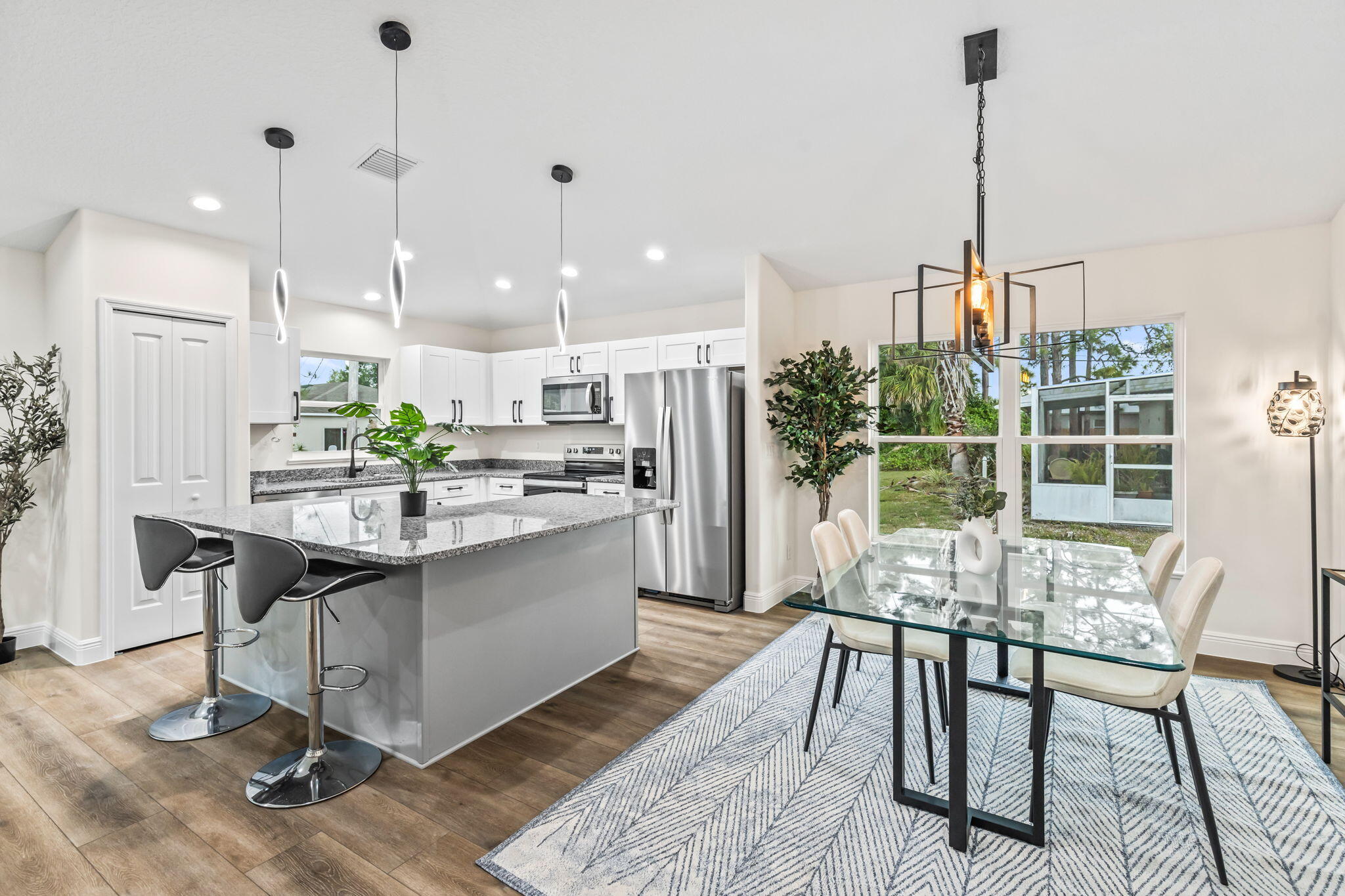 a kitchen with stainless steel appliances kitchen island granite countertop a table chairs and a wooden floor