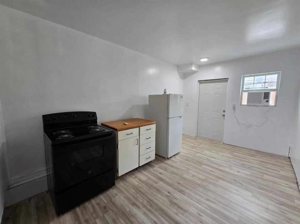 a view of a kitchen with refrigerator and wooden floor