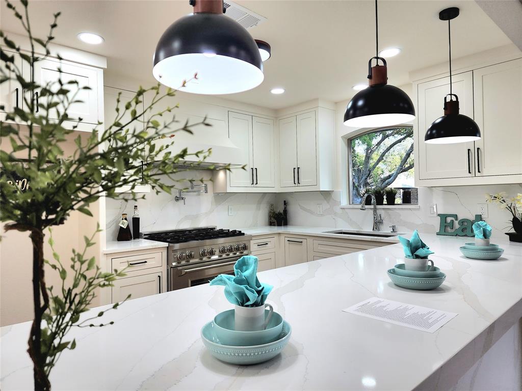 a kitchen with stainless steel appliances a stove a chimney a sink and cabinets