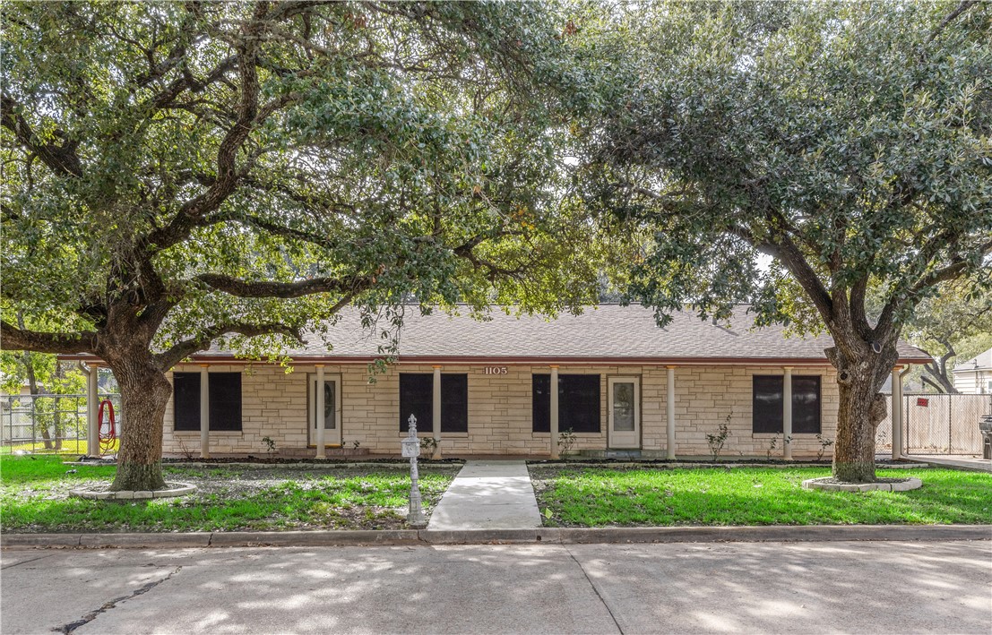 Single story home with a front yard and mature tre