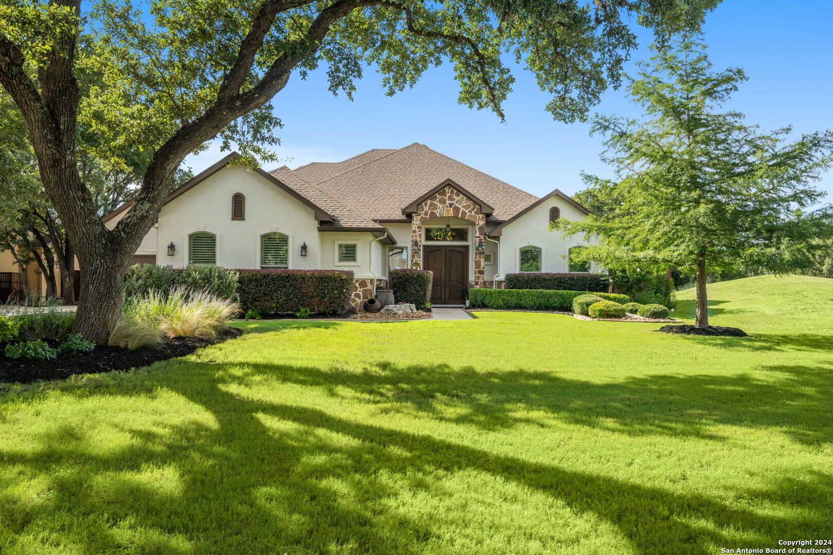 a view of a house with a big yard plants and large trees