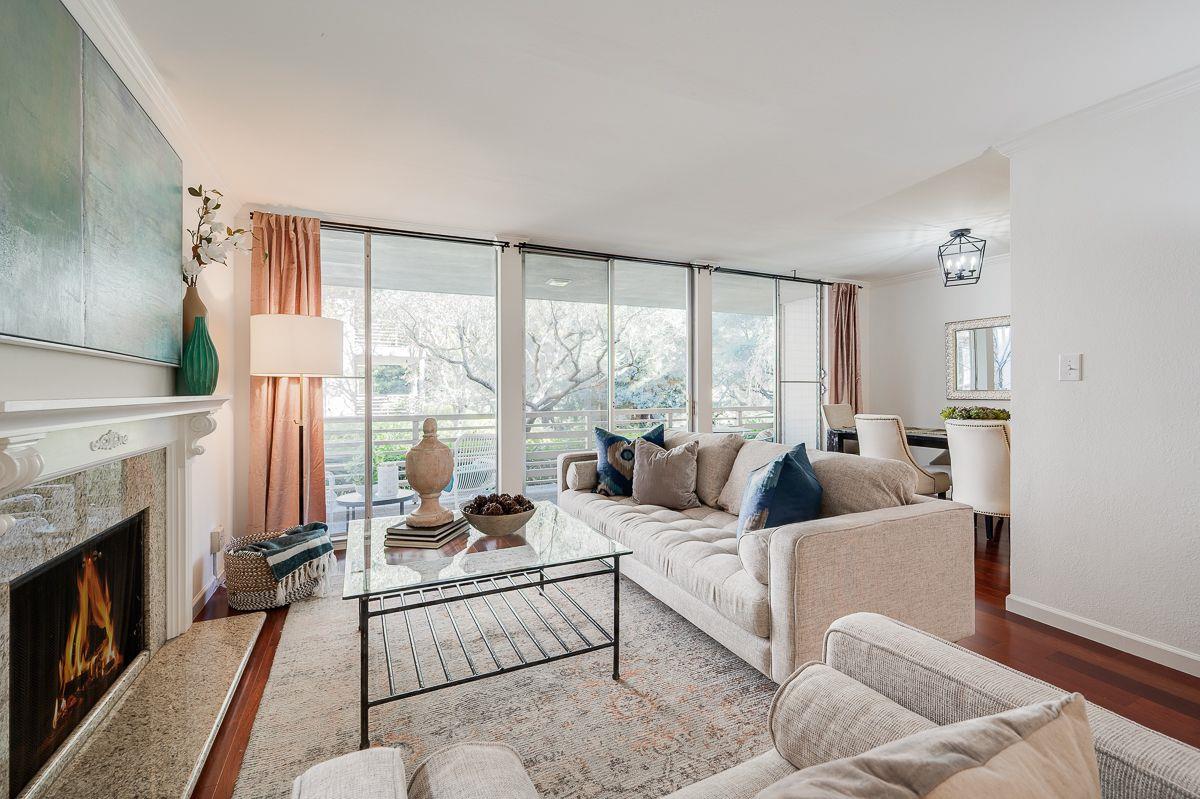 a living room with furniture large windows a fireplace and a rug