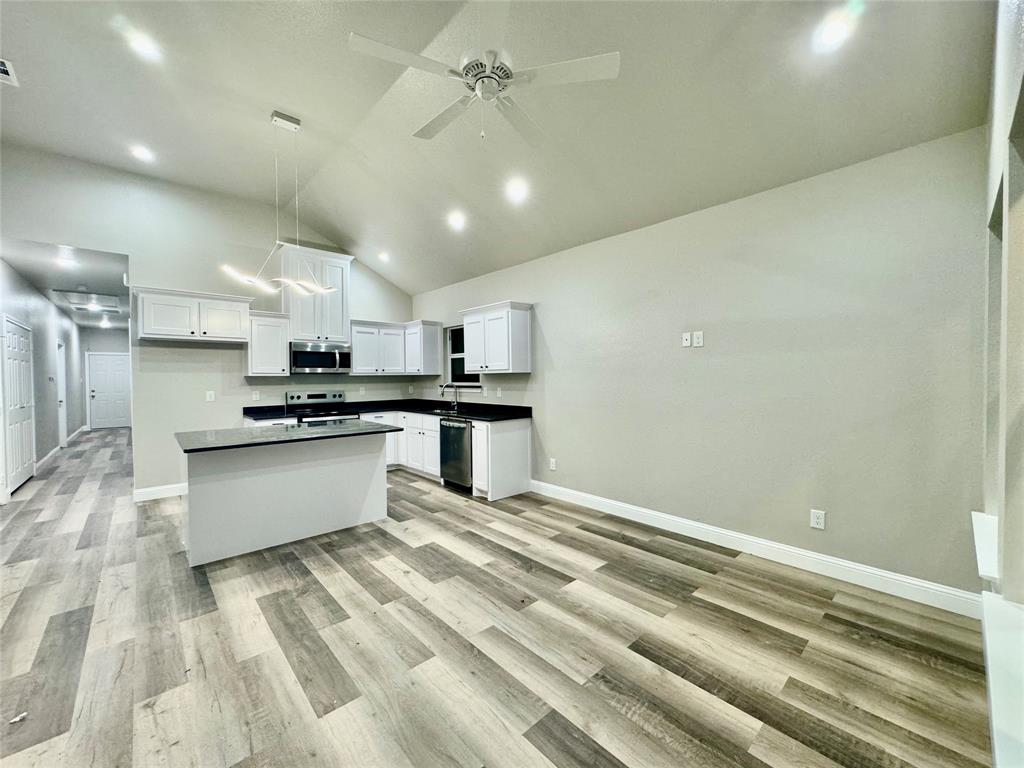 a large white kitchen with kitchen island a stove a sink and a refrigerator