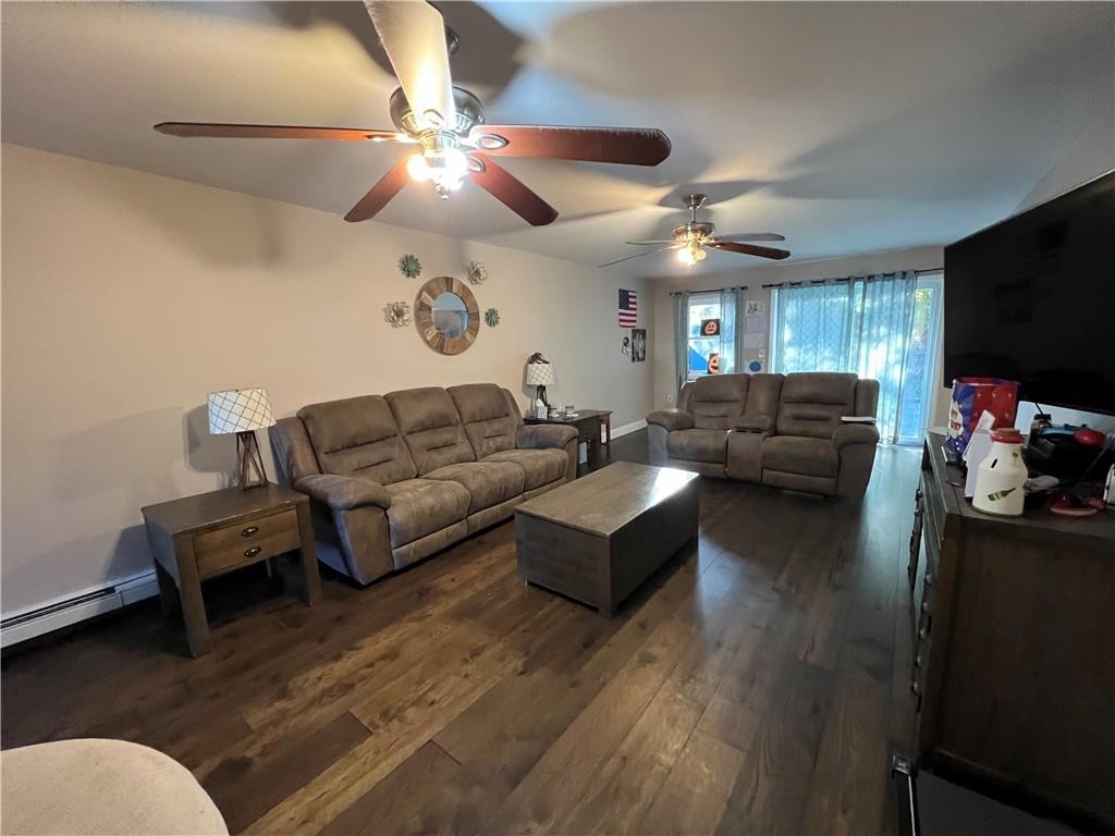 Living room with ceiling fan and dark hardwood / wood-style flooring