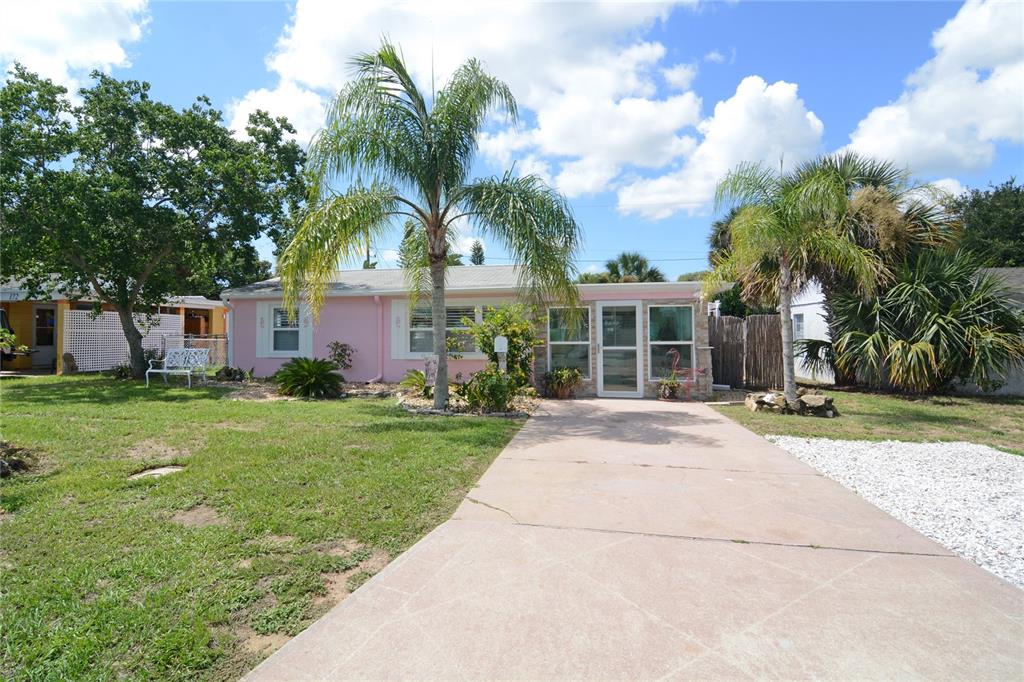 front view of a house with a yard and palm trees