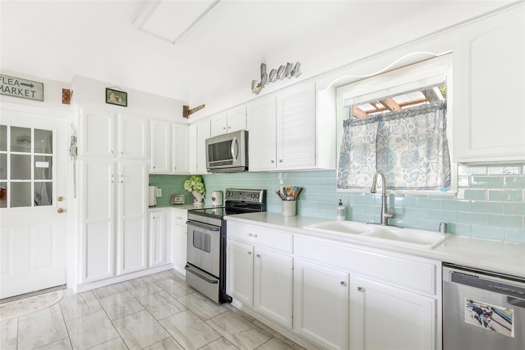The kitchen boasts beautiful Baby Blue/greenish Subway Tiles that perfectly complement its white cabinetry!