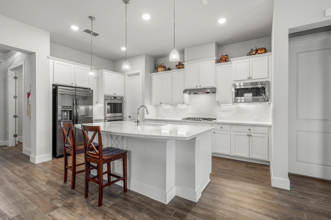 a kitchen with kitchen island granite countertop wooden cabinets and refrigerator