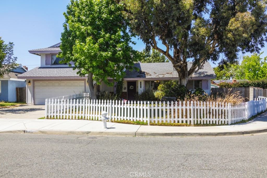 a view of a house with a small yard and a large tree