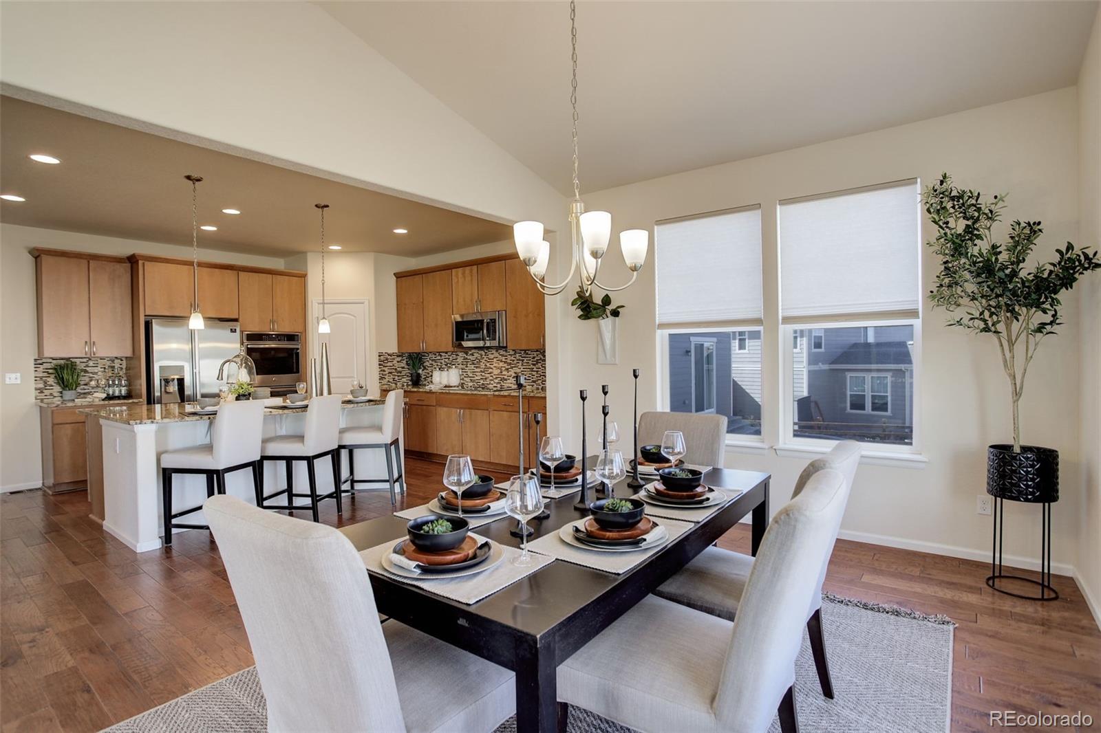 a dining room with stainless steel appliances kitchen island granite countertop a dining table chairs and a living room view