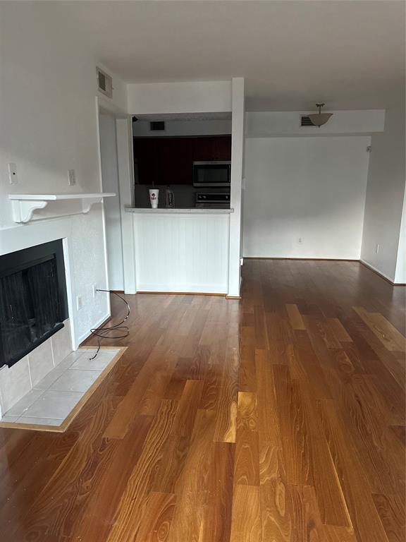 a view of empty room with wooden floor and fireplace