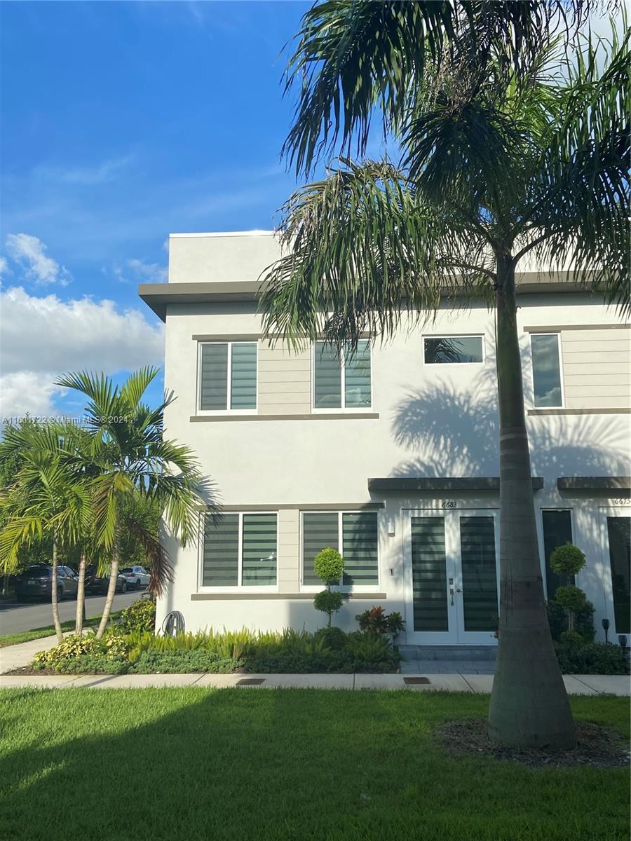 a front view of a house with a yard and palm trees