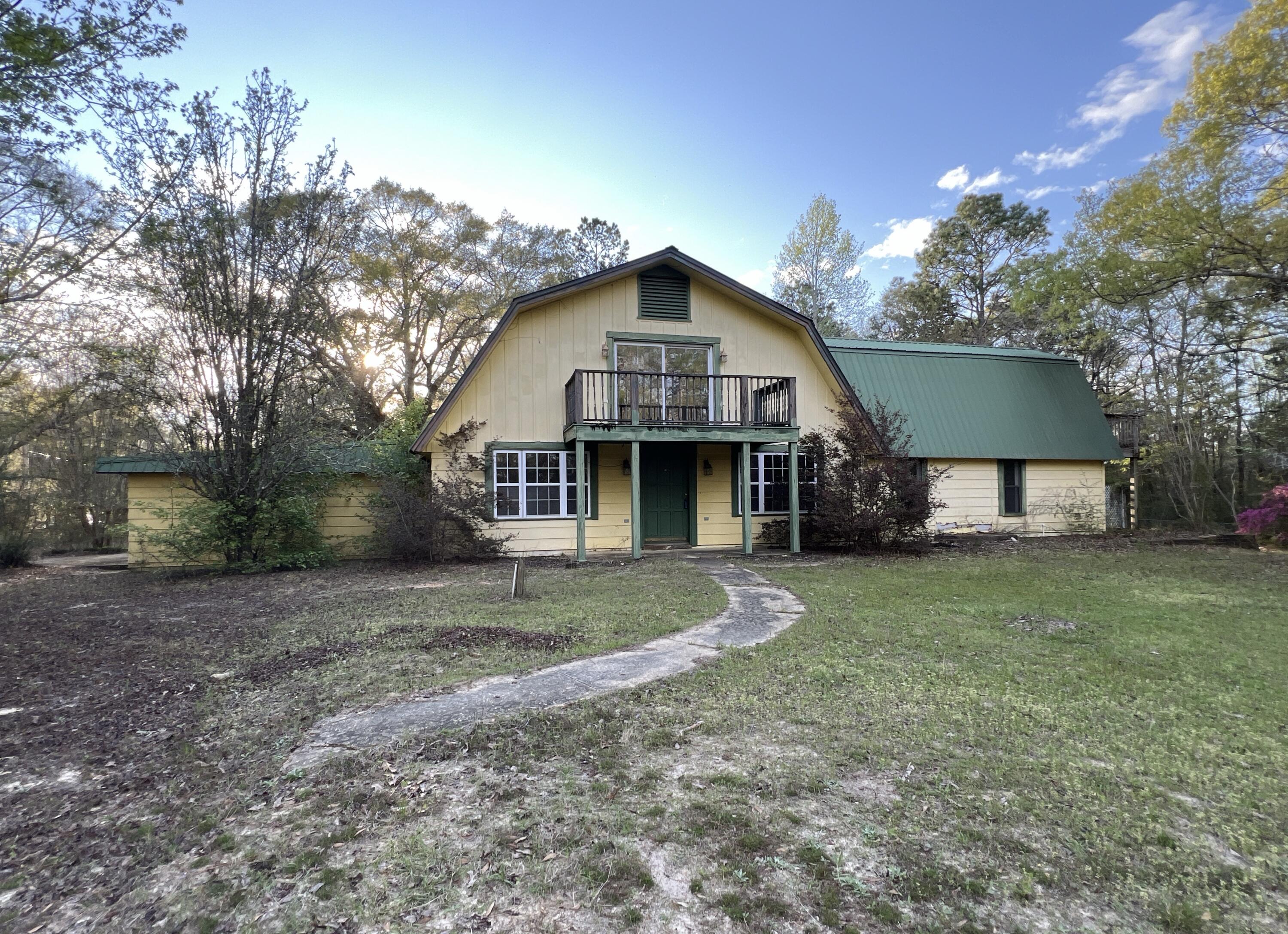 a front view of a house with a garden and trees