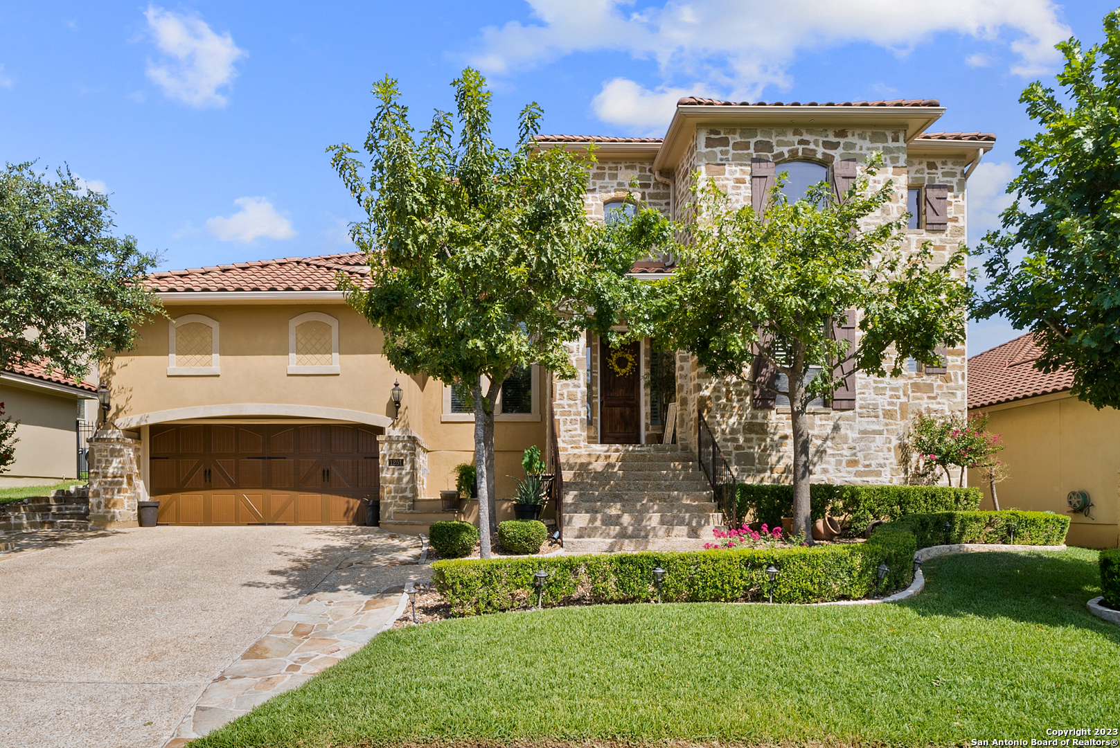 a front view of a house with a garden and a tree