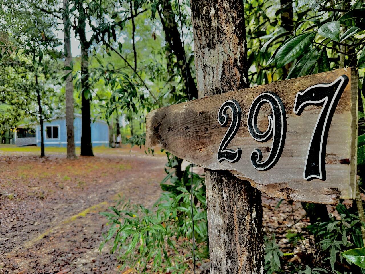 a view of a wooden house with a street sign and a tree