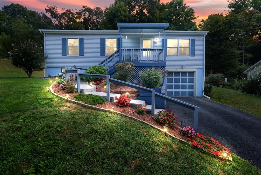 View of front of home with a lawn, a garage, and a porch