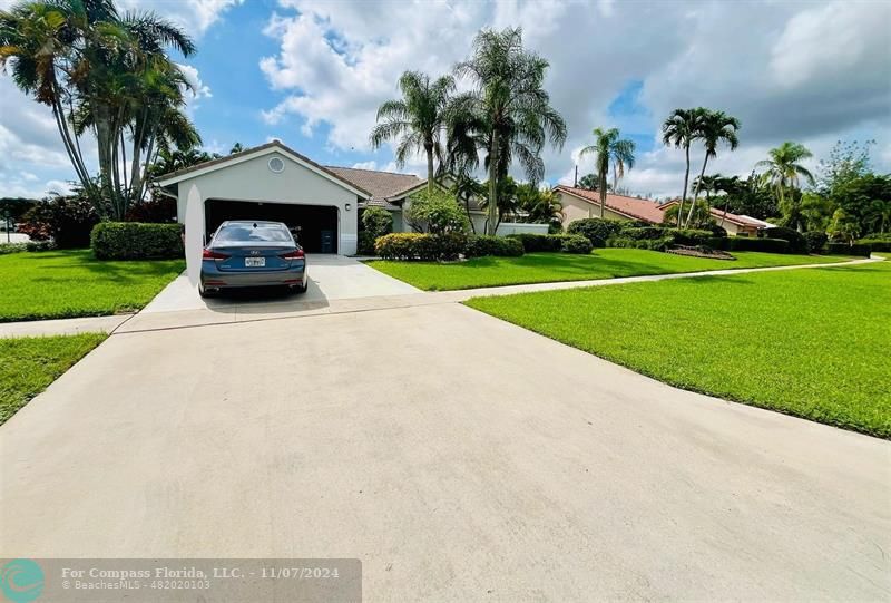 a white house with a small yard and palm trees