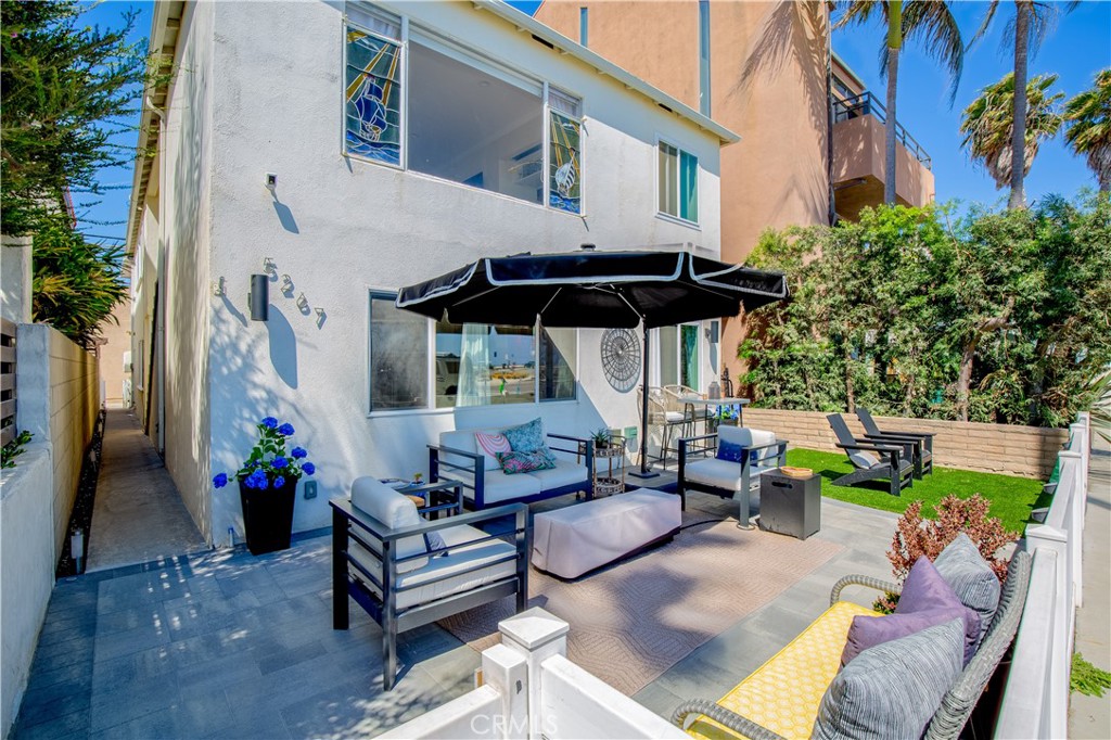 a view of a patio with couches table and chairs under an umbrella