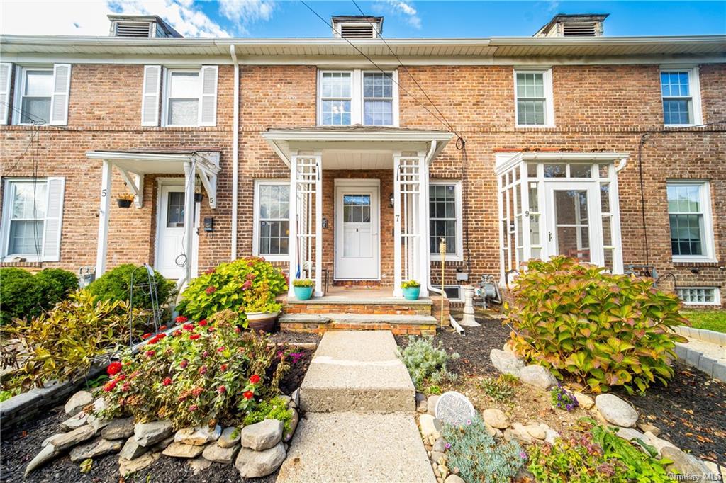 front view of a brick house with a large window and potted plants