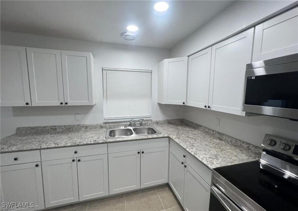 a kitchen with granite countertop a sink stove and cabinets