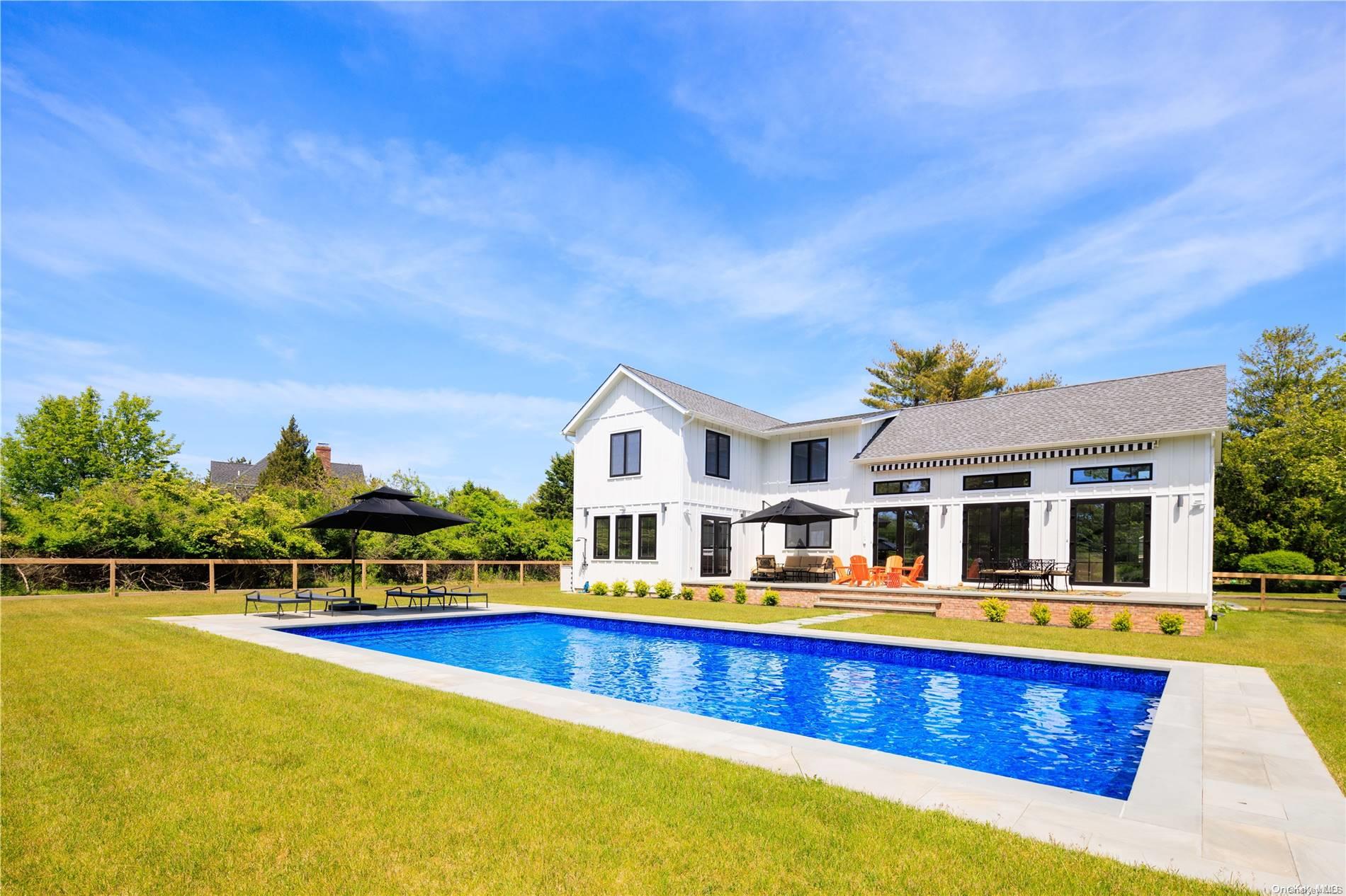 a view of swimming pool with outdoor seating and house in the background