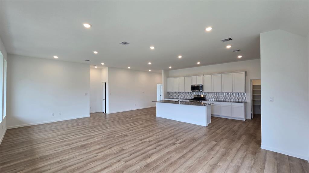 a view of kitchen with kitchen island stainless steel appliances wooden floor and window