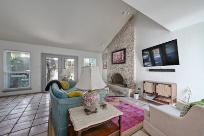 a living room with furniture a flat screen tv and a floor to ceiling window