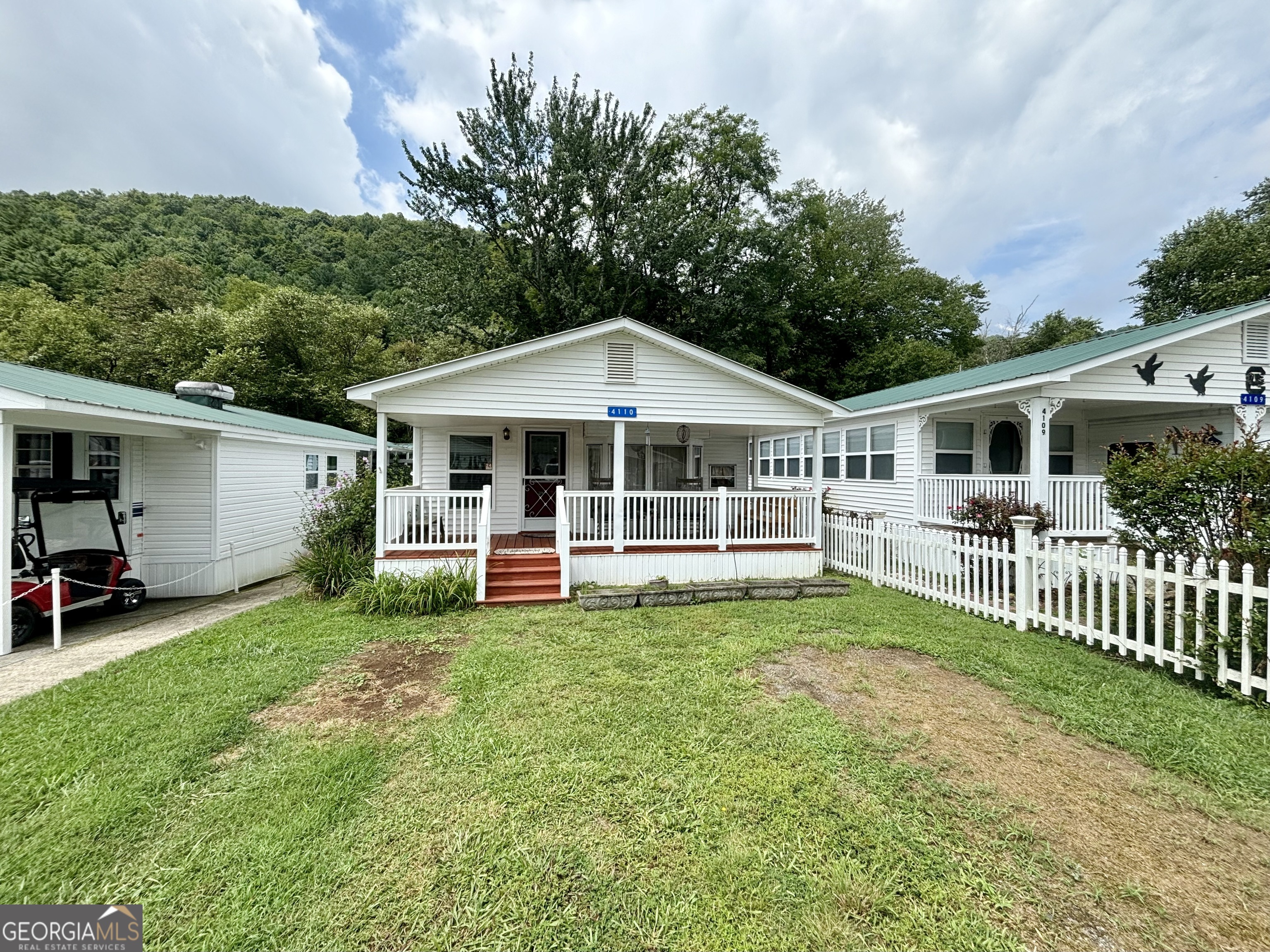 a view of a house with a yard and deck area under a large tree