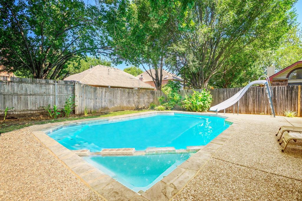 a view of a swimming pool with a lounge chair and the small yard