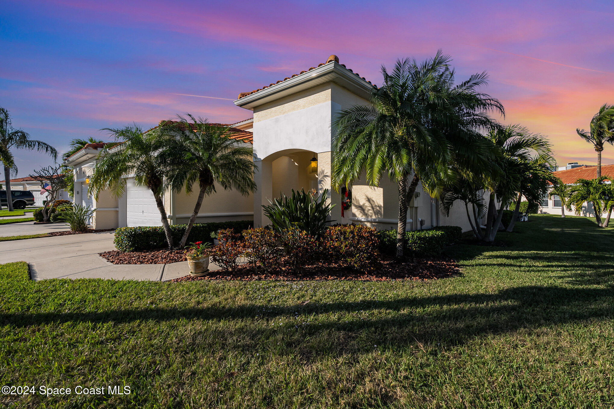 a couple of palm trees in front of house with a yard