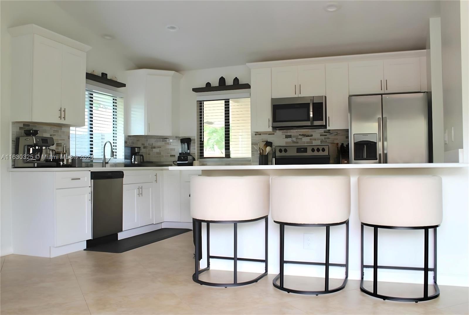 a kitchen with white cabinets and chairs