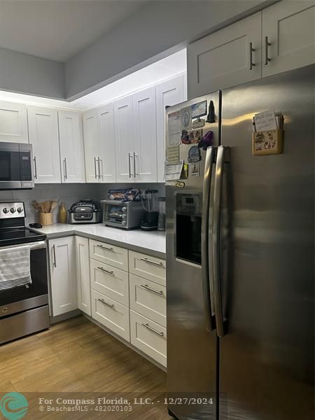 a kitchen with a refrigerator and white cabinets