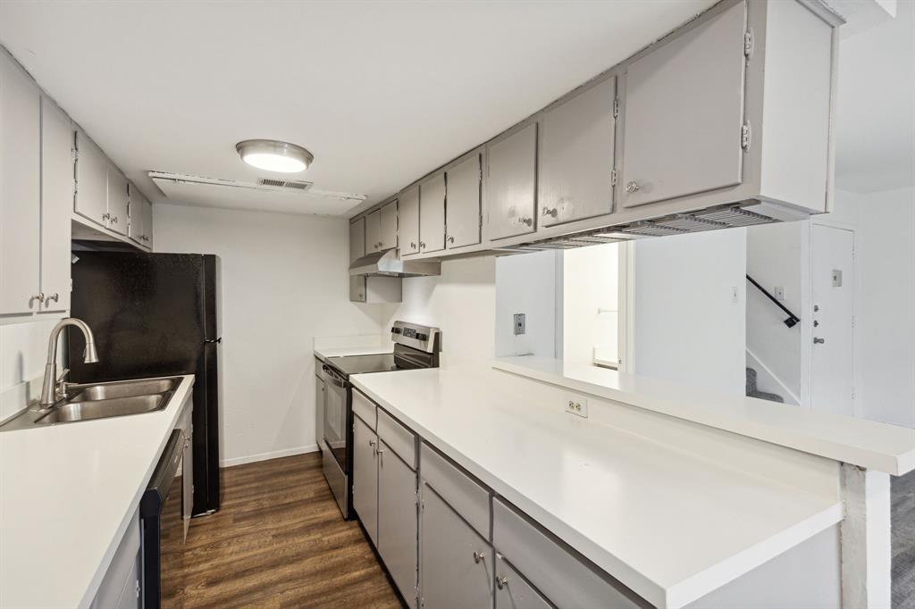 a kitchen with granite countertop a sink stainless steel appliances and white cabinets