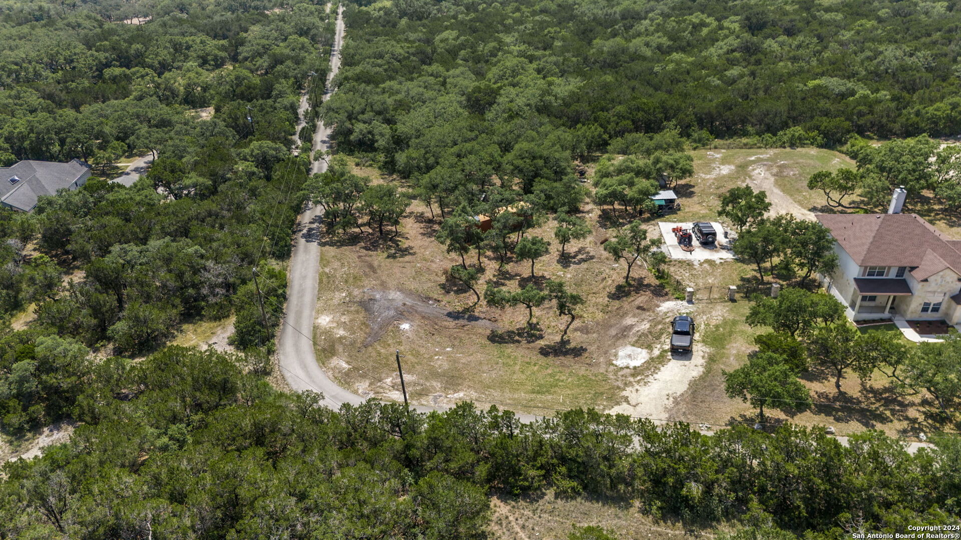 an aerial view of residential houses with outdoor space and trees all around