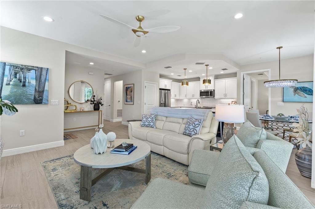 a living room with furniture kitchen view and a chandelier