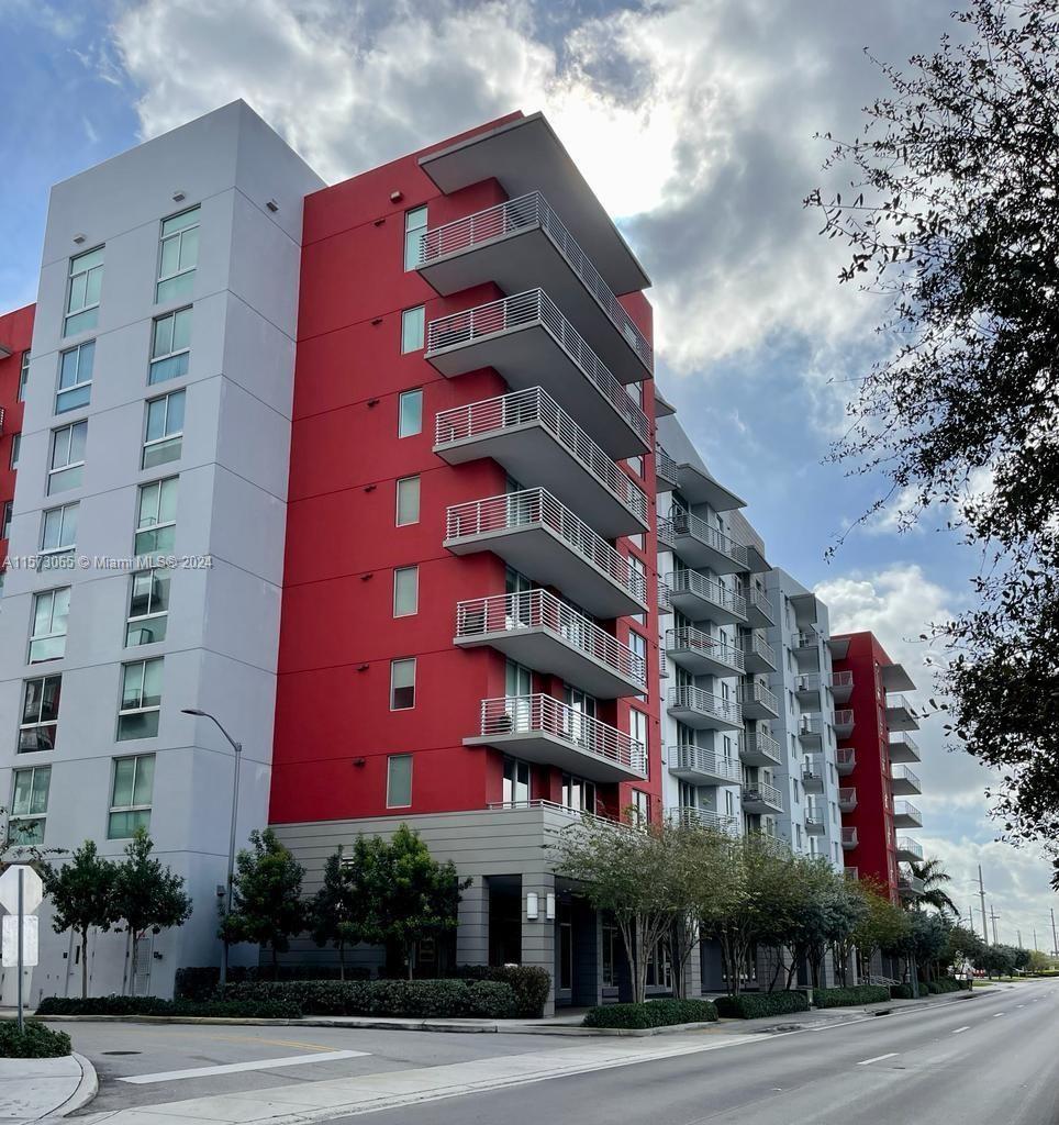 a front view of multi story residential apartment building with yard and parking