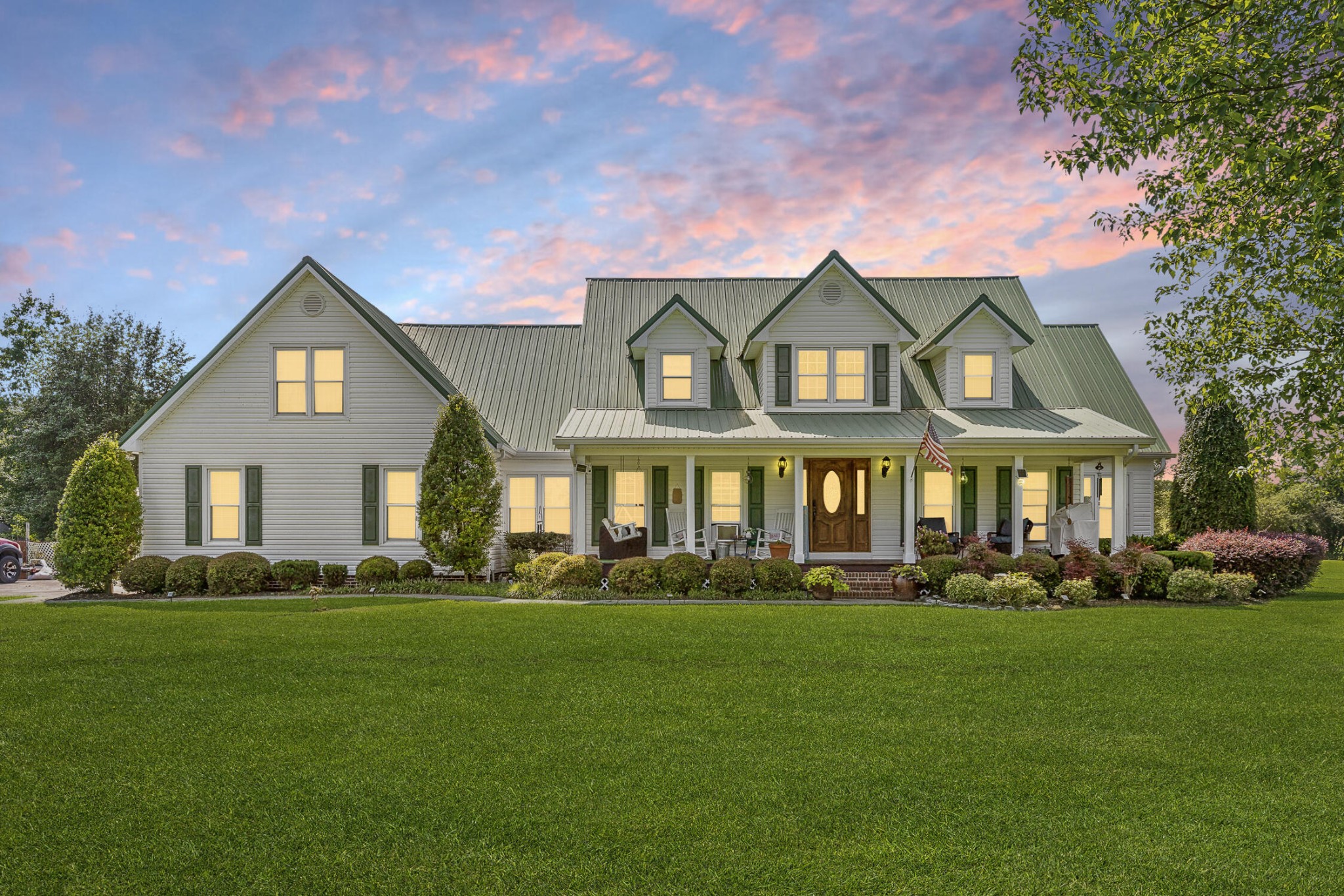 a front view of a house with a lots of trees and plants