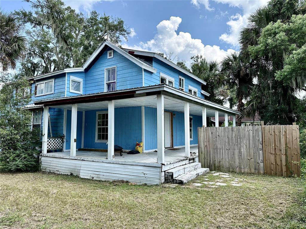 a view of a house with a yard balcony and wooden fence