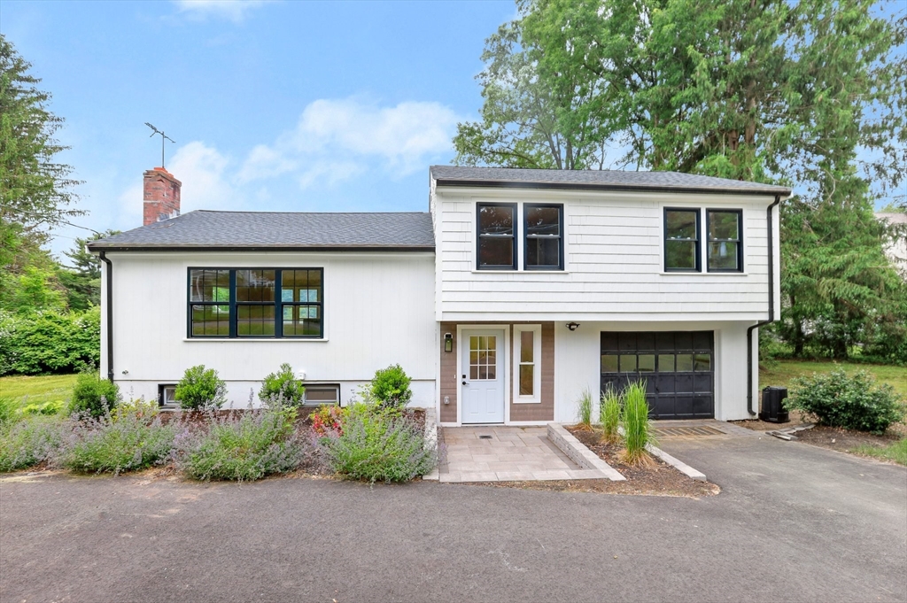 a front view of a house with a yard and potted plants