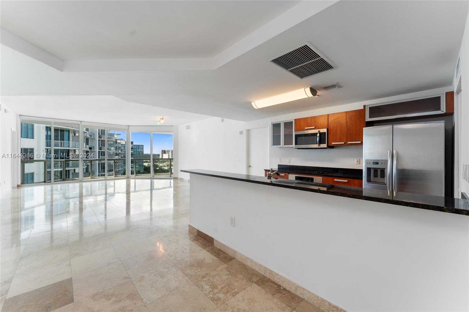 a living room with stainless steel appliances furniture a flat screen tv and a view of kitchen