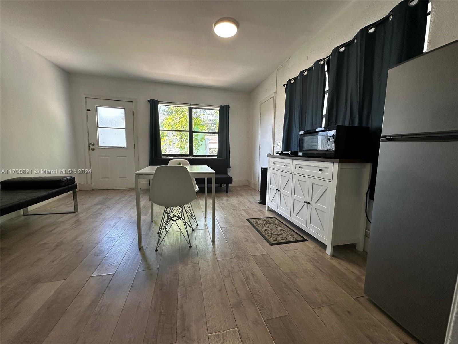 a living room with stainless steel appliances granite countertop a refrigerator a stove top oven a sink dishwasher and wooden cabinets with wooden floor